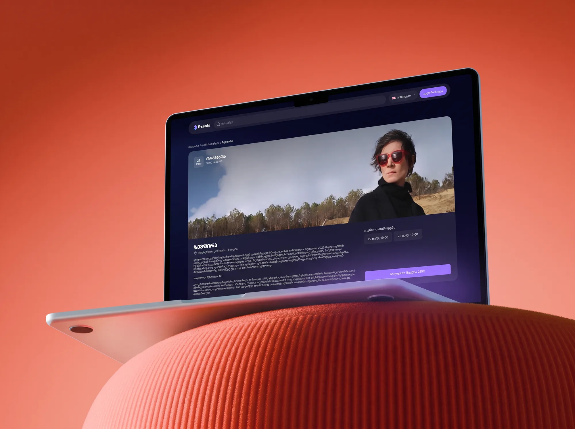 E-seats event page on a MacBook Air on a coral sofa arm