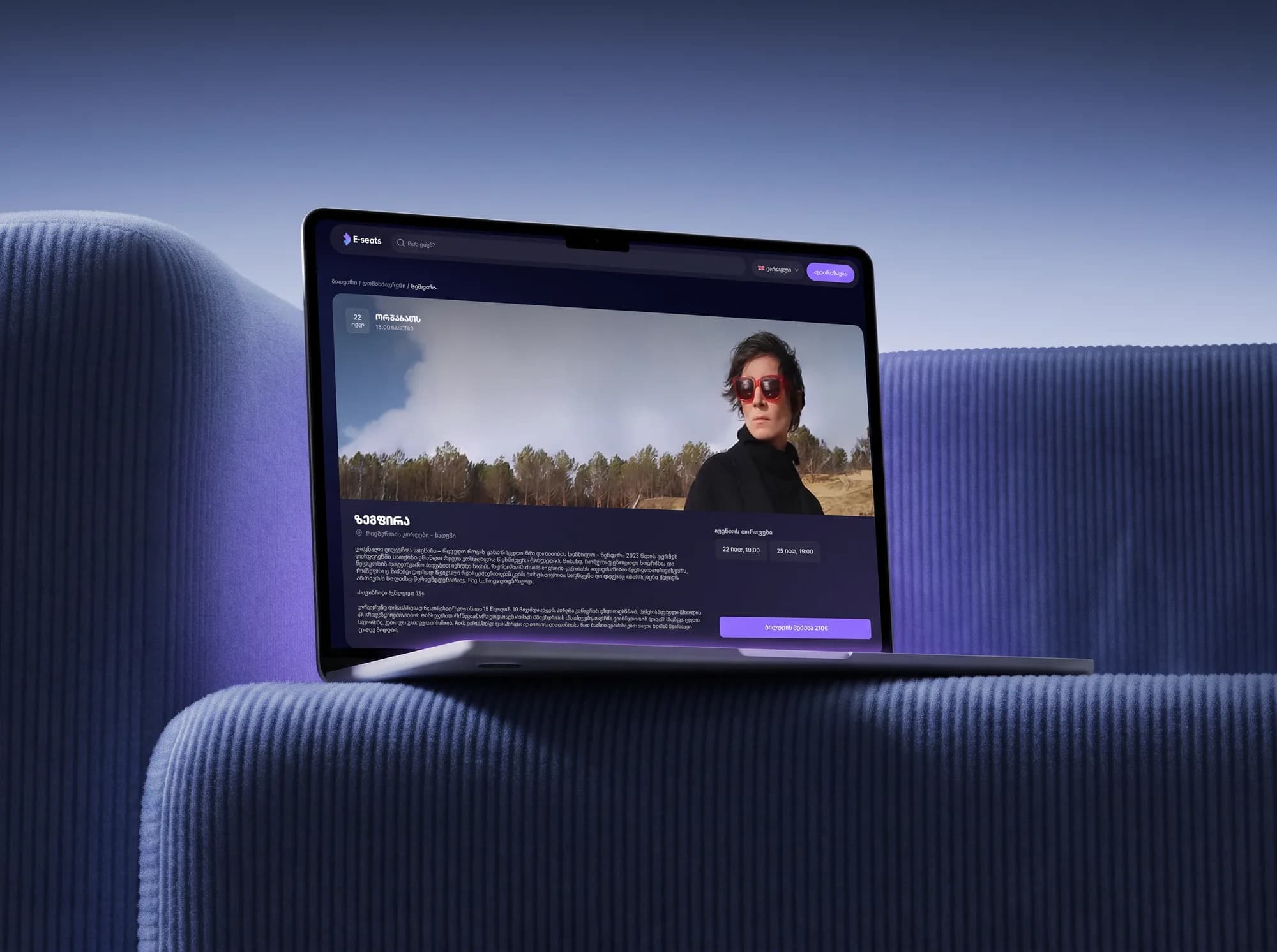 E-seats event page on a MacBook Air on a blue corduroy sofa, from the side